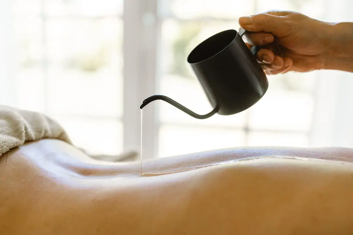 Anwendung Travemünde Eine Person gießt Öl auf einen Rücken.