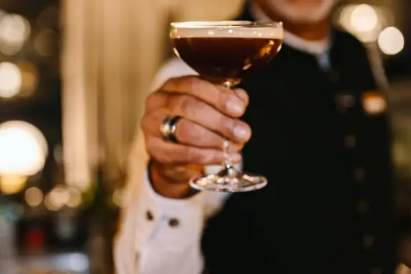 Ein Mann hält ein Glas mit Getränk und lächelt.