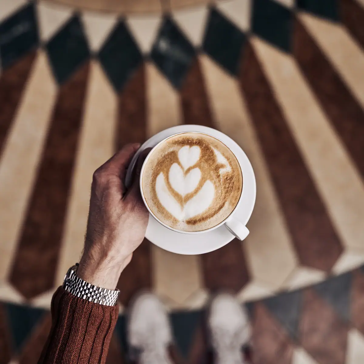 Eine Person hält eine Tasse Kaffee.
