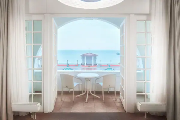 Balkon Ein Zimmer mit einem Tisch und Stühlen, das einen Blick auf das Meer bietet.