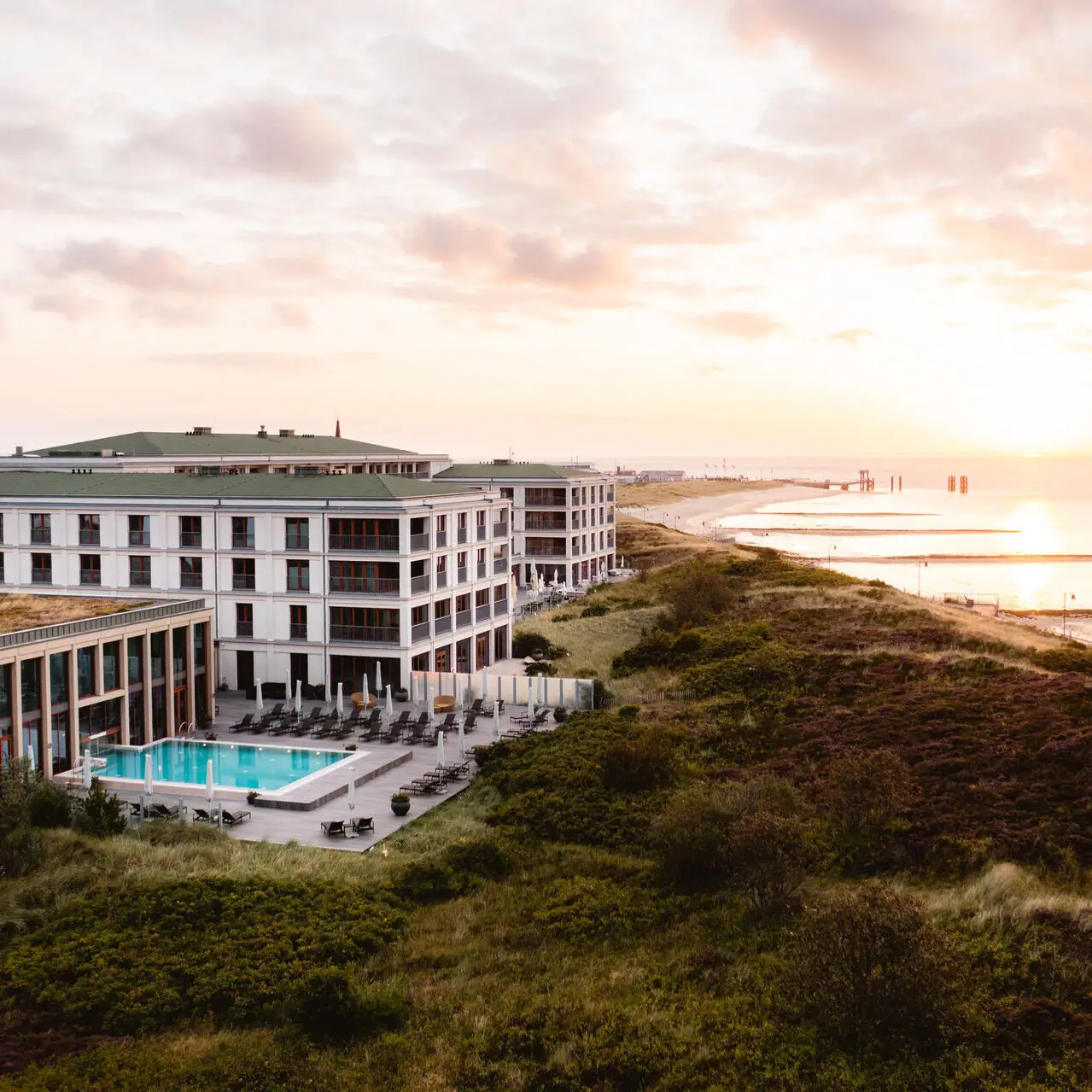 A-ROSA Sylt Gebäude mit Pool am Wasser im Freien bei bewölktem Himmel.