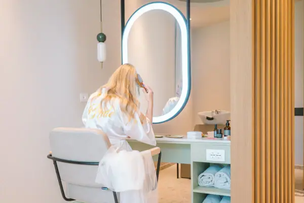 SPA-Suite im A-ROSA Gardasee Eine Frau im Bademantel kämmt ihr Haar vor einem Spiegel.