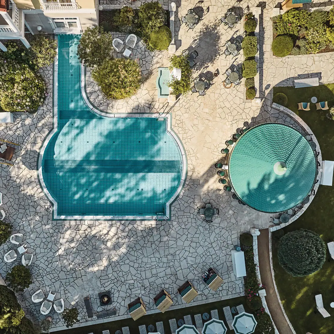 Pool mit Liegestühlen und Bäumen im Hintergrund.