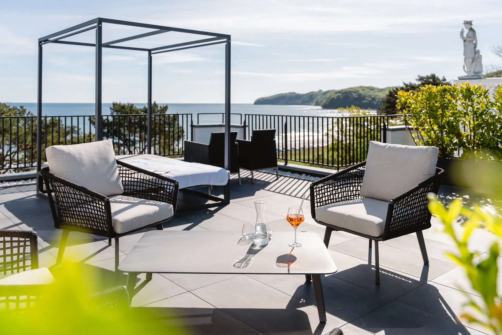 A-ROSA Ceres am Meer Terrasse Eine Terrasse mit Stühlen und einem Tisch auf einem Deck mit Blick auf das Meer.