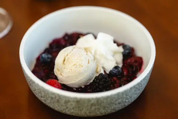 Dessert Eine Schüssel mit Obst und Eiscreme auf einem Tisch.