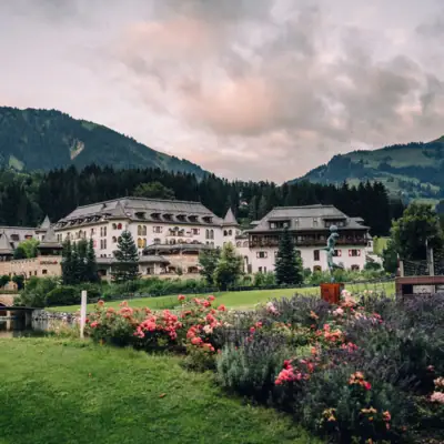Großes Gebäude mit Garten und See im Vordergrund.