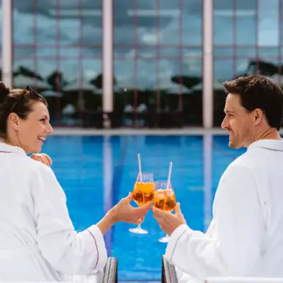 Day SPA in Travemünde Ein Mann und eine Frau in Bademänteln halten Getränke.