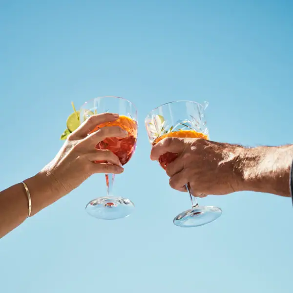 Ein Paar Hände hält Weingläser.