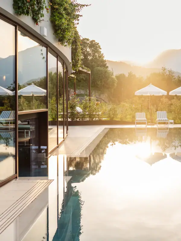 Ein Pool mit Liegestühlen und Sonnenschirmen vor einem Haus.