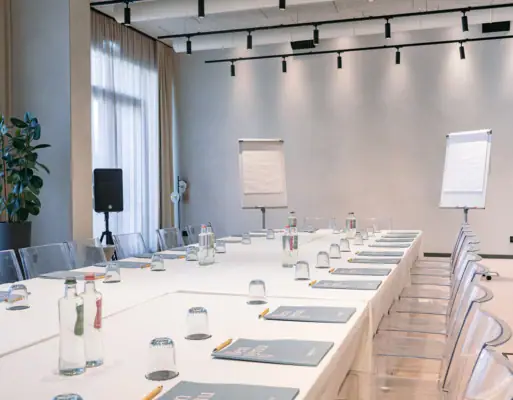 Konferenzraum mit weißen Tischen und Stühlen.