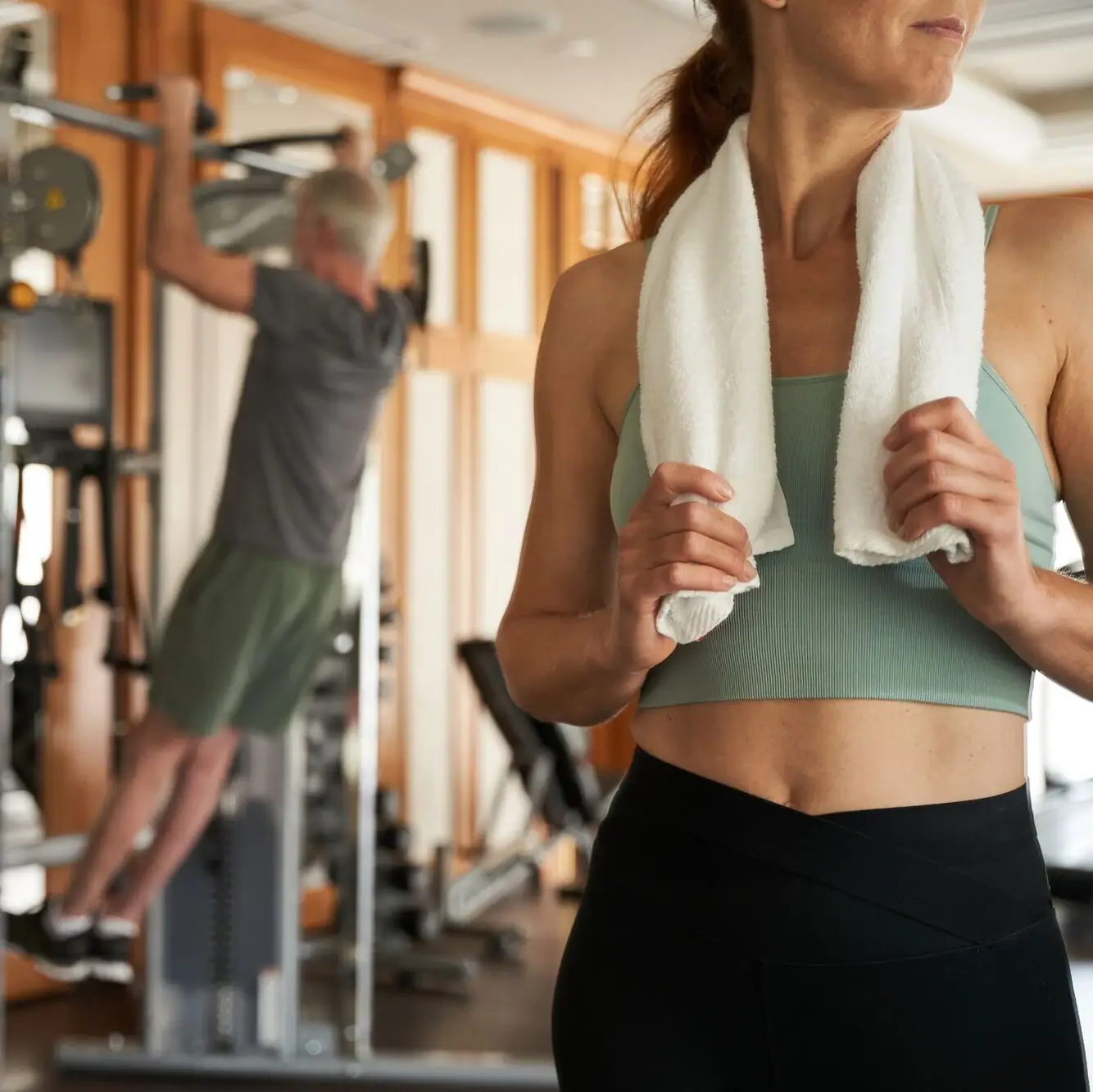 Webformat-paar-sport-training-fitnessraum-strandidyll-heringsdorf.jpg Frau hält ein Handtuch um den Nacken im Fitnessstudio.