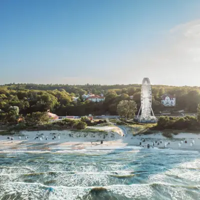 Strand mit Riesenrad und Bäumen im Hintergrund.