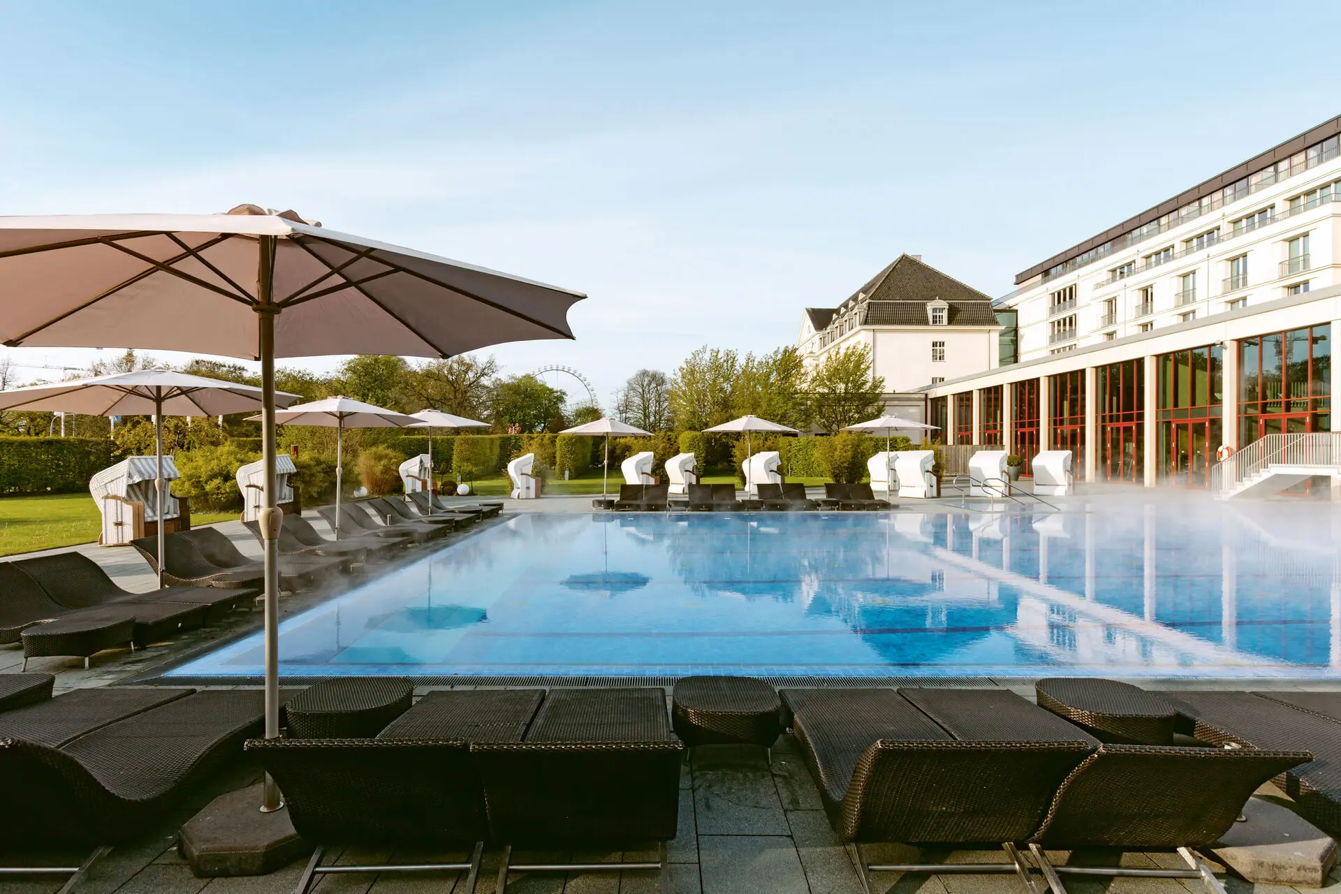 Außenpool Großes weißes Gebäude mit Pool und Bäumen im Vordergrund.