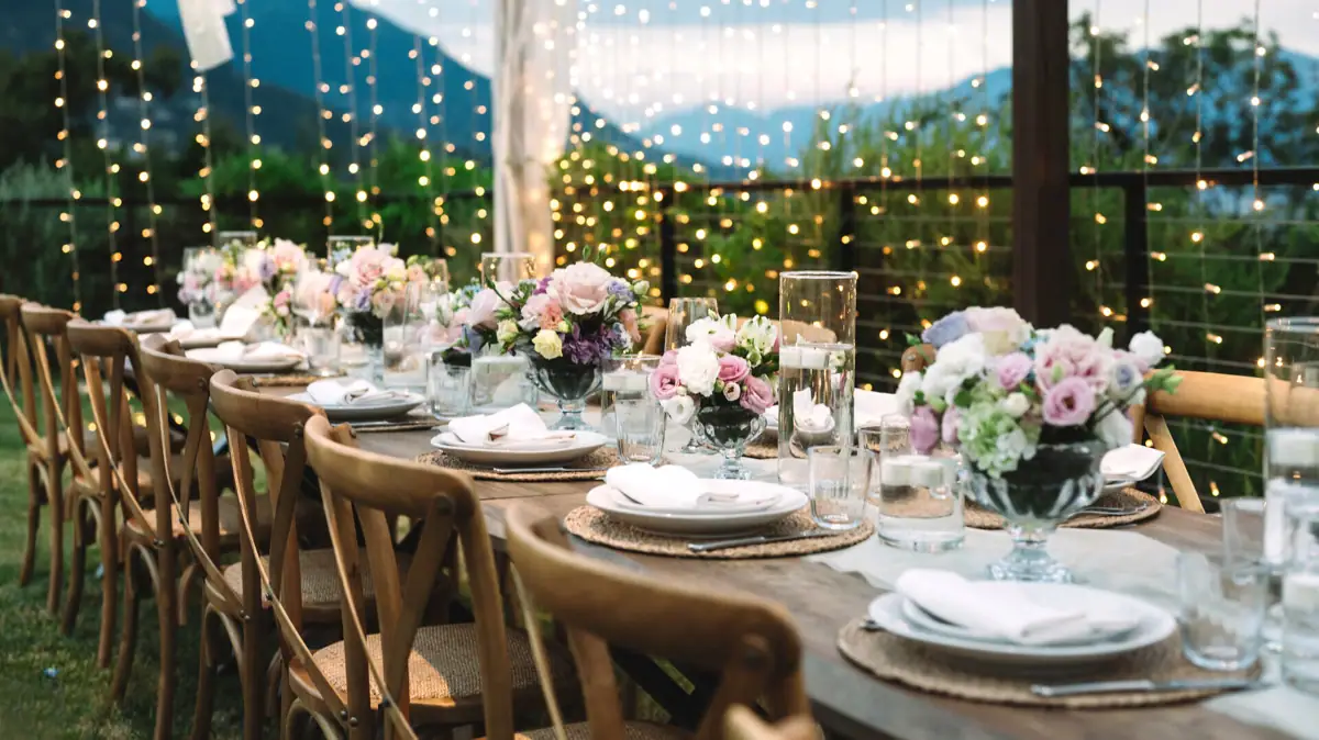 Ein festlich gedeckter Tisch mit Geschirr, Gläsern und einem Blumenarrangement als Mittelpunkt.