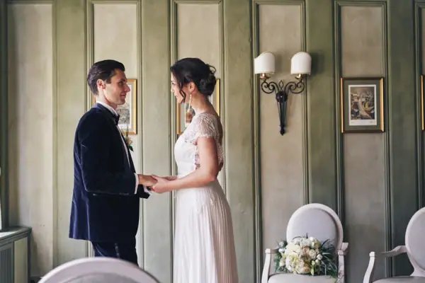 Ein Mann und eine Frau in Hochzeitskleidung halten sich an den Händen.