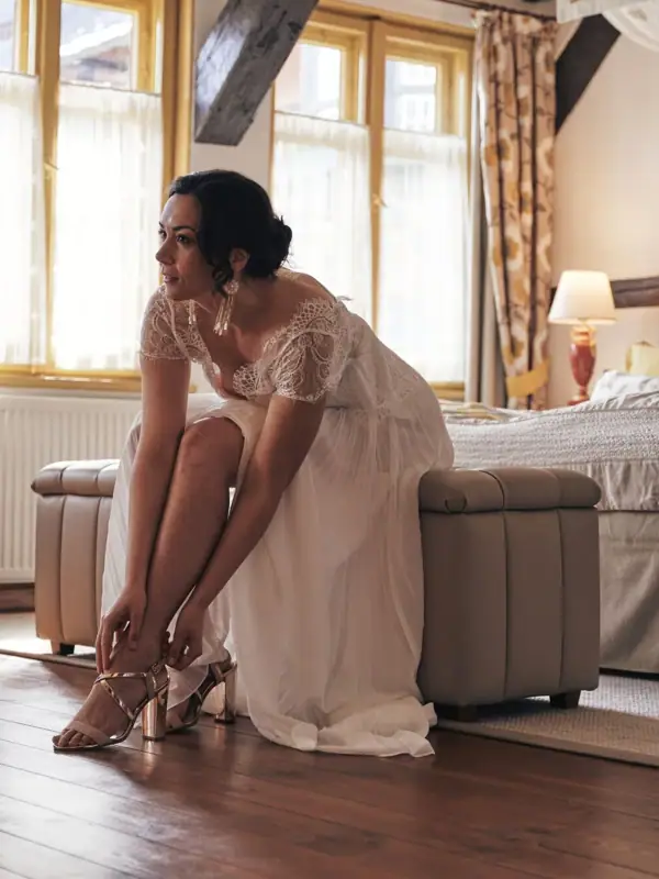 Frau in einem weißen Kleid sitzt auf einem Holzboden.