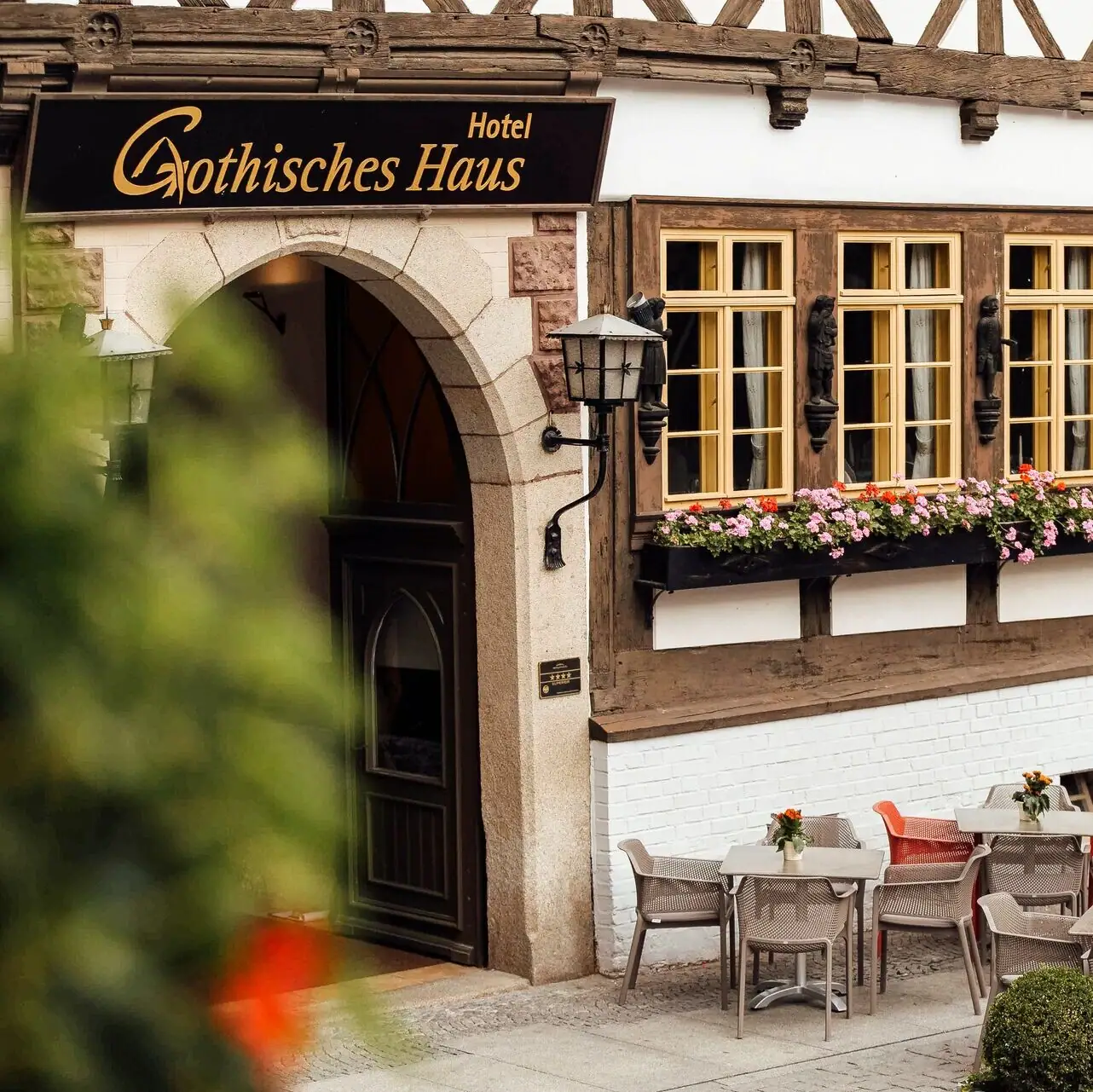 Eine Gruppe von Menschen sitzt an Tischen im Freien vor einem Gebäude.