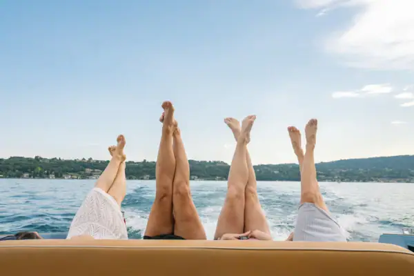 Entspannung auf dem See Vier Frauen strecken ihre Beine vom Boot aus über den Gardasee.