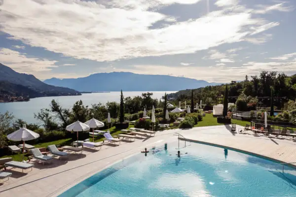 Außenpool im A-ROSA Gardasee Ein Pool mit Liegestühlen und Sonnenschirmen am Wasser.