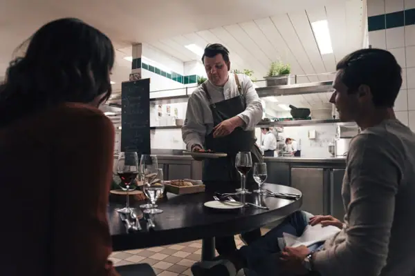 Küchentisch Gothisches Haus Ein Mann serviert einer Gruppe von Menschen Essen.