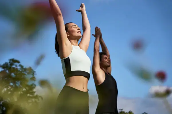 Ein Mann und eine Frau mit erhobenen Armen im Freien.