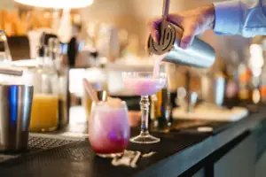 Bar Eine Person gießt ein Getränk in ein Glas.