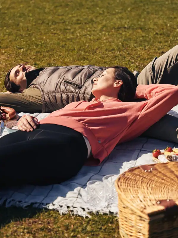 Ein Mann und eine Frau liegen auf einer Decke im Park.