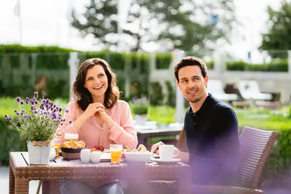 Frühstück auf der terrasse Ein Mann und eine Frau sitzen an einem Tisch mit Essen.