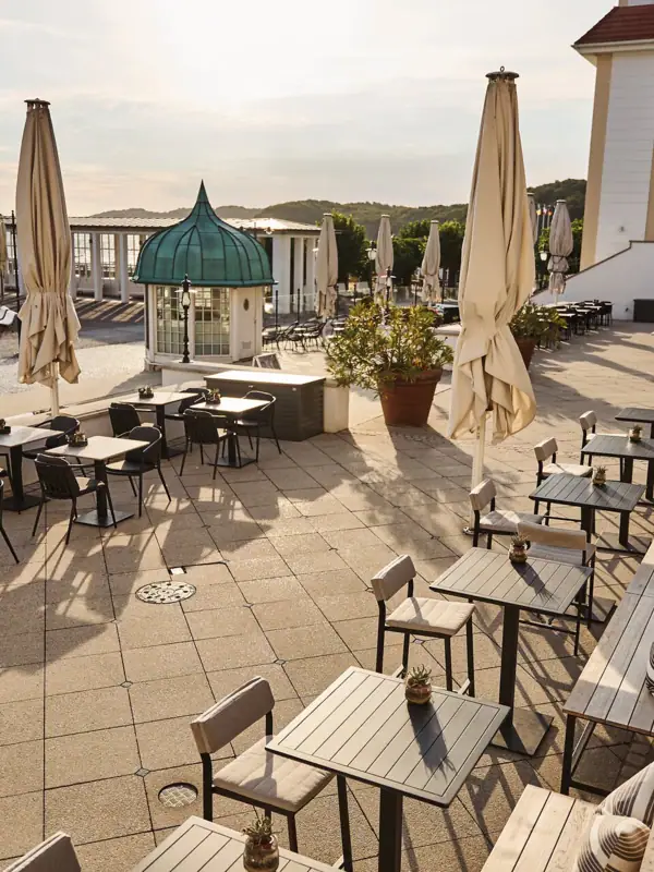 Eine Terrasse mit Tischen und Sonnenschirmen.