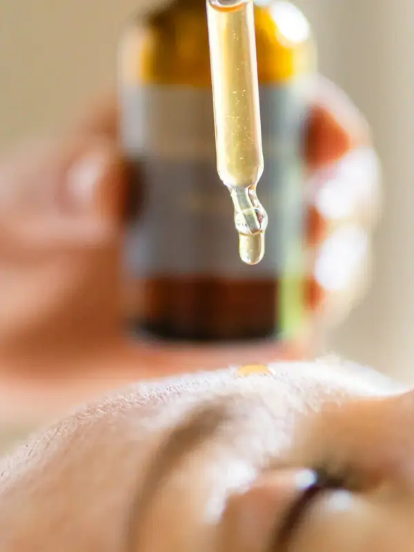 Eine Person träufelt eine Flüssigkeit in das Gesicht einer anderen Person.