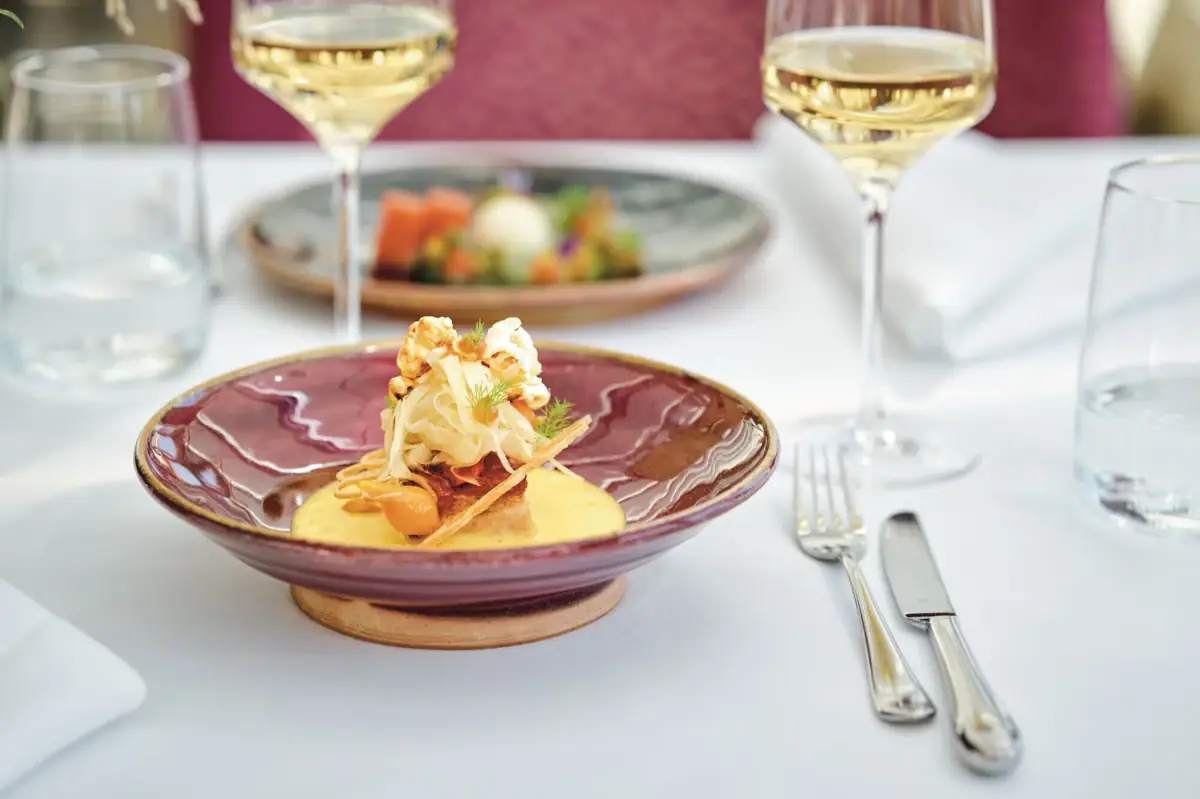 Ein Teller mit Speisen und ein Weinglas auf einem Tisch.