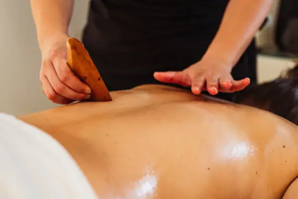 Eine Person massiert den Rücken einer anderen Person mit einem Massagegerät.