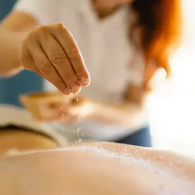 Treatments Eine Person streut Salz auf den Rücken einer anderen Person.
