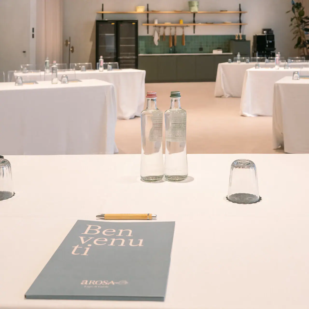 Tagen am Gardasee Ein Tisch mit weißem Tischtuch, Wasserflaschen und Vasen.