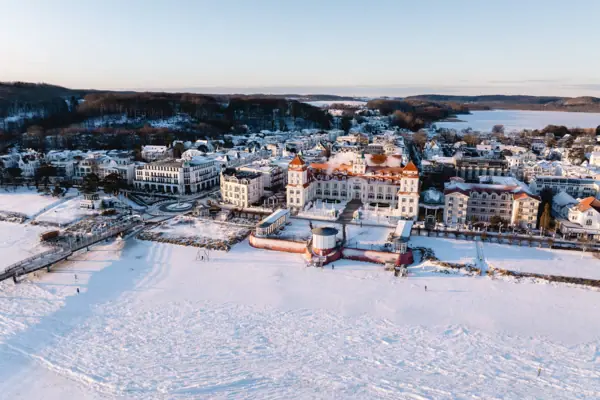 Kurhaus Binz Schneebedeckte Stadt mit Gebäuden und einem Gewässer im Winter.