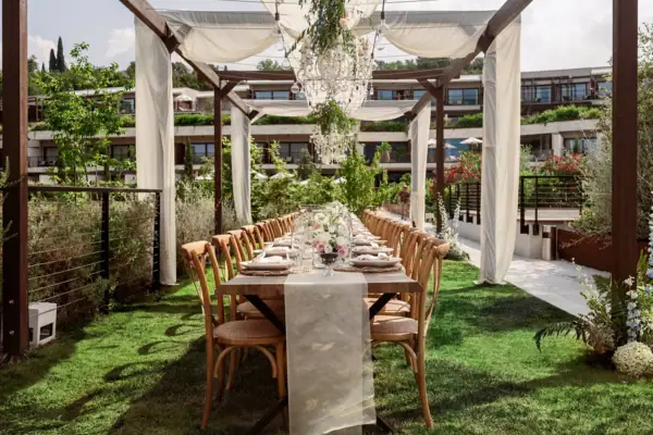 Dinner unter der Pergola Hochzeitstafel unter einer mit Stoffbahnen und Blumen geschmückten Pergola im Garten des A-ROSA Gardasee.