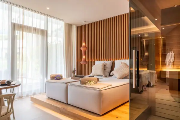 Ein Zimmer mit einem Bett und einer Glastür zum Innenraum einer Sauna..