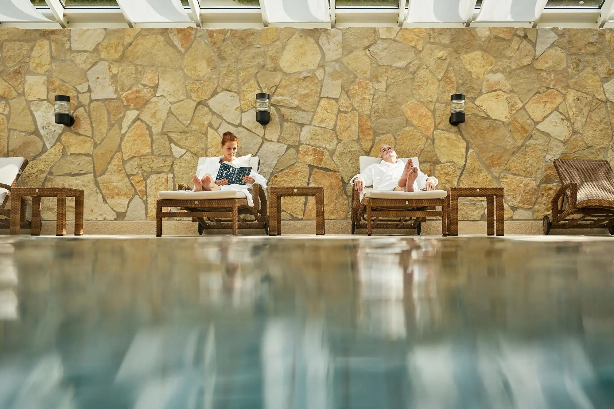 Webformat-wellness-spa-paar-auf-liegen-am-poolrand-strandidyll-heringsdorf.jpg Ein Mann und eine Frau sitzen auf Stühlen am Pool.