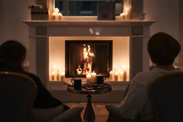 Kamin Ein Kamin mit Kerzen und einem Paar, das davor sitzt.