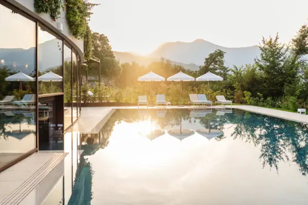 Wellnessbereich Ein Pool mit Liegestühlen und Sonnenschirmen vor einem Haus.