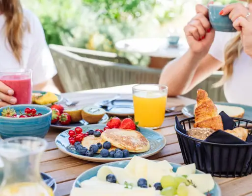 Frau hält eine Tasse Kaffee und einen Teller mit Essen.