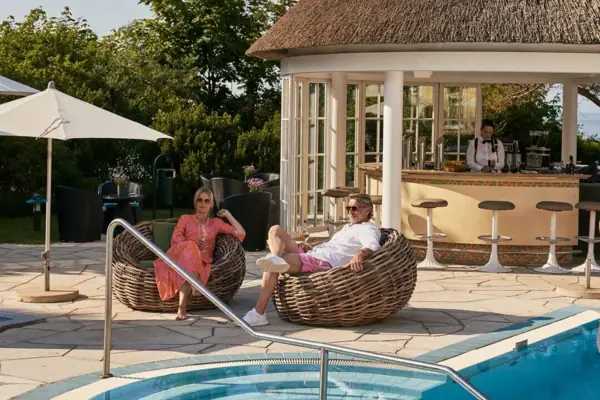 Ein Mann und eine Frau sitzen auf Stühlen nahe einem Pool.