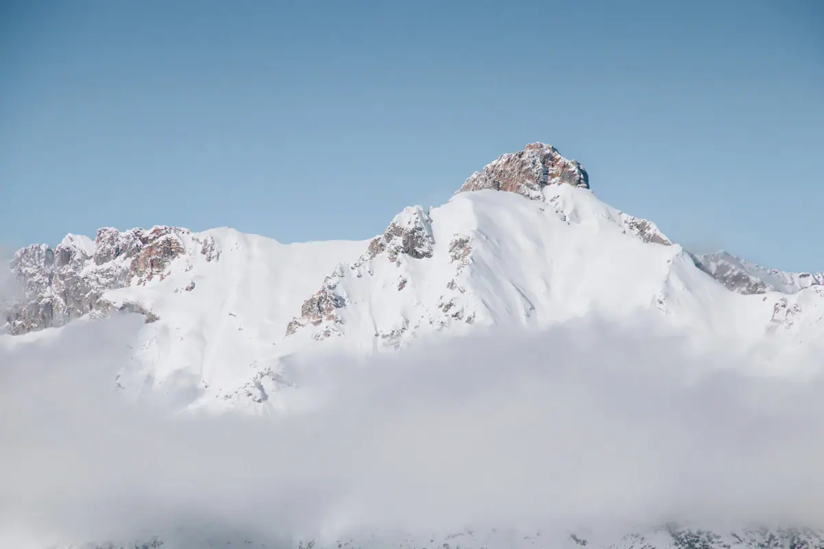 Schneebedeckter Berggipfel mit Wolken.