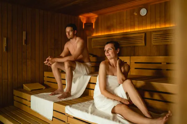 Sauna Travemünde Ein Mann und eine Frau sitzen auf einer Bank in einer Sauna.