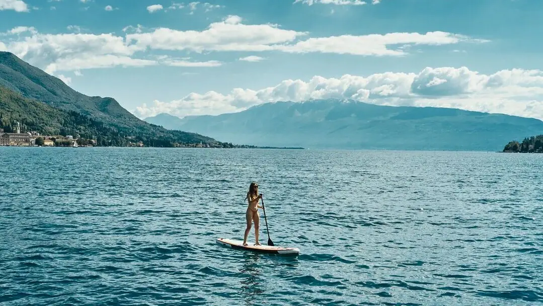 Wassersport Gardasee Eine Frau auf einem Paddleboard im Wasser.