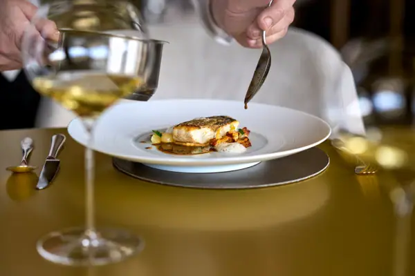 Kilian Stuba Eine Person hält einen Löffel über Essen auf einem Teller.