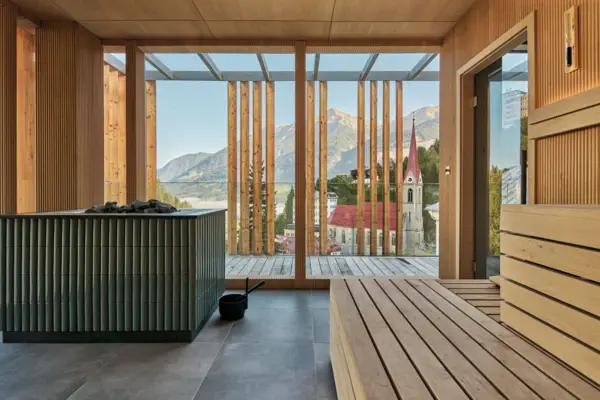 Panoramasauna im Straubinger Grand Hotel Bad Gastein Ein Raum mit Sauna und Blick auf Berge und eine Kirche.