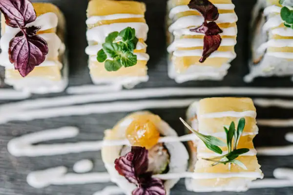 Sushi Ein Teller Sushi mit weißer Soße und Blumen.