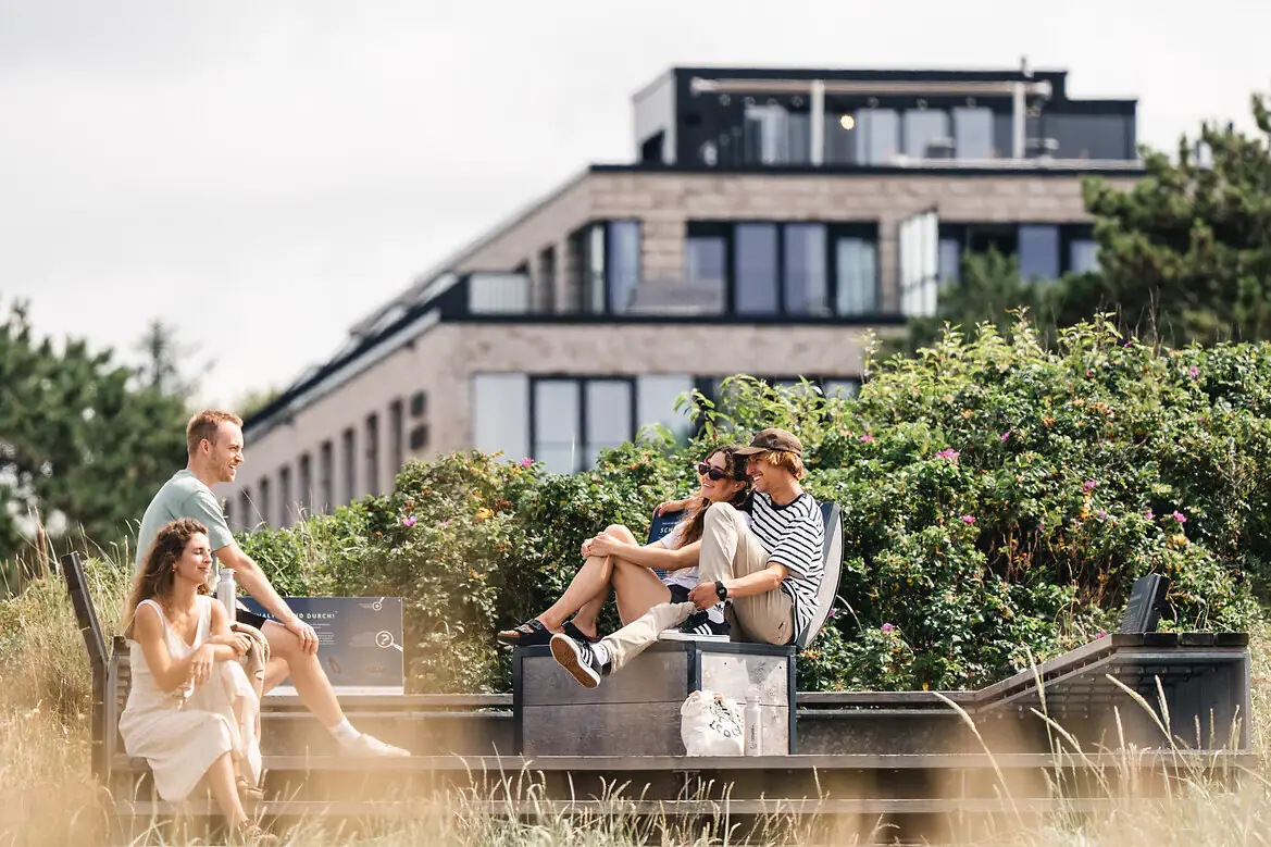 Eine Gruppe von Menschen sitzt auf einer Bank im Freien.