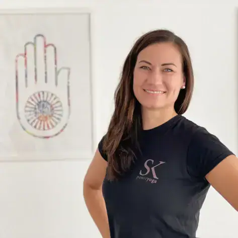 Eine lächelnde Frau mit der Hand in der Hüfte.